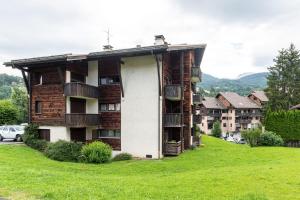 an apartment building on a hill with a green field at Appartement proche La Clusaz in Saint-Jean-de-Sixt