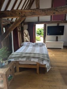 a bedroom with a large bed and a tv at Cosy listed barn in peaceful country village in Grandborough