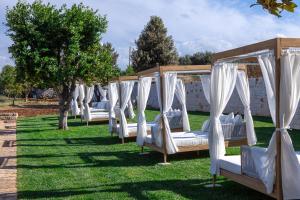 a row of white beds sitting in the grass at Masseria Valentina in Ostuni