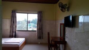 a bedroom with a bed and a television and a window at Sokcheav Guesthouse in Senmonorom