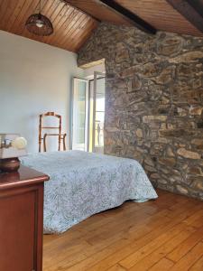 a bedroom with a bed and a stone wall at La Morada del Cabo Peñas FOLU-GOZON-LUANCO in Luanco
