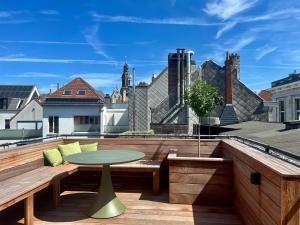 a patio with a table and benches on a roof at Cathedral view from the bathtub in Antwerp