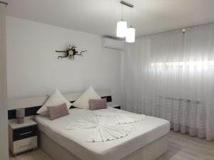 a white bedroom with a bed with a flower on it at Vila Marius 2 Mai in 2 Mai