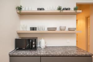 a kitchen with a microwave on a counter with dishes at Central Avenue Residence Kaunas in Kaunas +22 photos
