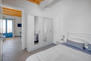 a white bedroom with a large bed and a bathroom at Ramos Wellside Apartments in Serifos Chora