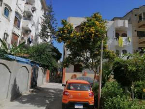 un'auto arancione parcheggiata su una strada accanto a un albero di Loyalty apartment a Dumyat al Jadidah