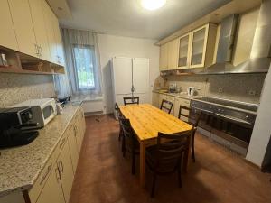 a kitchen with a wooden table and chairs in it at Villa Rila Borovets with Hot Pool, Jacuzzi & Sauna by BookVillaBG in Borovets