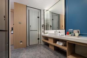 a bathroom with a sink and a mirror at Microtel by Wyndham Qingdao Huangdao in Qingdao +19 photos