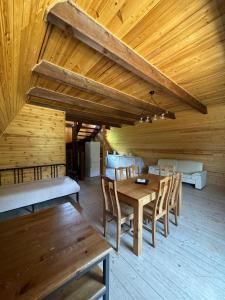 a room with a wooden ceiling with a table and chairs at Borjomi Cottage Sadgeri in Sadgeri