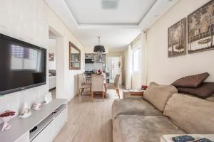 a living room with a couch and a tv and a kitchen at Apto com piscina privativa no centro in Balneário Camboriú