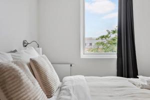 a white bed with white pillows and a window at Cosy 4-Person Apartment in The Heart of Aarhus in Aarhus +29 photos