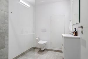 a white bathroom with a toilet and a shower at Cosy 4-Person Apartment in The Heart of Aarhus in Aarhus
