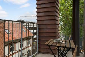 a balcony with a wooden table and a building at Cosy 4-Person Apartment in The Heart of Aarhus in Aarhus