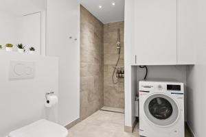 a white bathroom with a washing machine in a bathroom at Beautiful City Center Apartment w Balcony in Aarhus