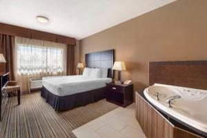 a hotel room with a bed and a bath tub at Best Western Plus Peace River Hotel & Suites in Peace River