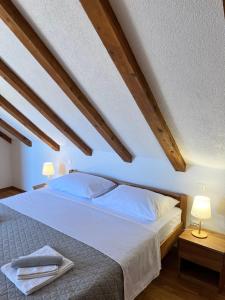 a bedroom with a large white bed with wooden ceilings at Didova kuća, kamena vila sa bazenom u blizini Rogoznice in Podorljak +80 photos
