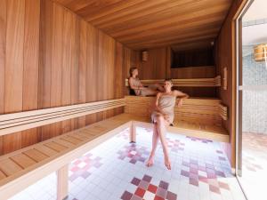 a woman is sitting in a sauna at Aiden by Best Western Clermont-Ferrand Hotel & Spa in Clermont-Ferrand