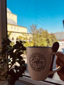 a person holding a coffee cup in a window at Edion Center Apartment in Shkodër