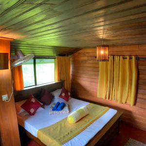 a small bed in a room with a wooden ceiling at Cottage Home Belihuloya in Balangoda