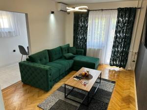 un soggiorno con un divano verde e un tavolo di M2-apartments a Kraljevo
