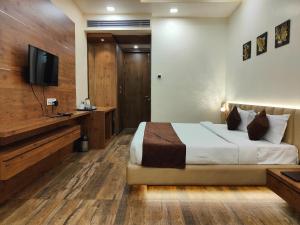 a bedroom with a bed and a flat screen tv at RIVERSIDE MEADOWS in Vidisha