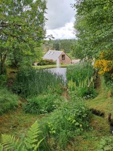 un laghetto di fronte a una casa con un edificio di Boghead Cottage: Holiday Cottage in Royal Deeside a Banchory