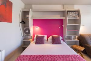 a bedroom with a bed with a pink headboard at The Originals Boutique ,Hôtel de Ré in Sainte-Marie-de-Ré