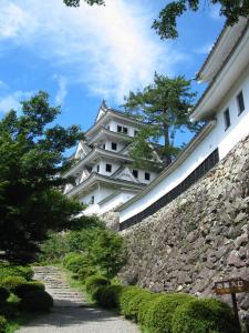 un grande edificio bianco, seduto accanto a un muro di pietra di Miharaya Ryokan a Gujo