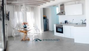 a white kitchen with a table and a sink at villa EYEONSUNSET - MAGICAL PLACE -PRIVATE pool -SEA and SUNSET VIEW -NO WIND - in Mikonos