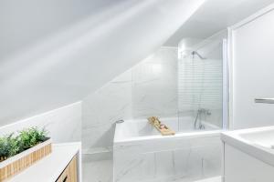 a white bathroom with a tub and a sink at Maison 8 personnes - Parking - Métro 7 et Rer B à 6 minutes in La Courneuve
