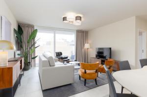 een woonkamer met een bank, een tafel en stoelen bij Leader De Haan - Casselbergh Residences in De Haan