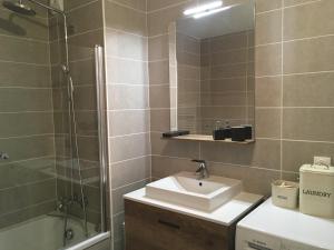 a bathroom with a sink and a shower and a mirror at Appartement neuf, balcon plein sud in Oz +4 photos