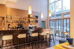 a bar in a restaurant with a woman standing behind the counter at NH Hamburg Horner Rennbahn in Hamburg
