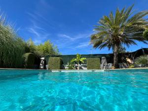 a swimming pool with blue water and palm trees at La Romantica in Congéniès