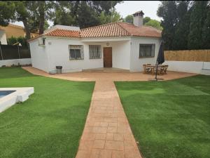 a small white house with a green lawn at La Cañada in Partida de La Cañada
