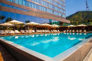 a swimming pool with chairs and umbrellas in front of a building at Radisson Blu Iveria Hotel in Tbilisi City