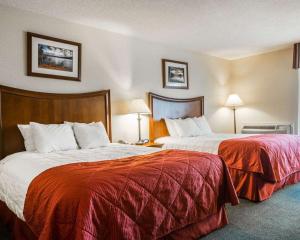 ein Hotelzimmer mit 2 Betten mit roter Bettwäsche in der Unterkunft Clarion Inn & Suites at the Outlets of Lake George in Lake George