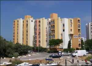 a large building with cars parked in a parking lot at Carnon-plages - Agréable Studio cabine in Mauguio
