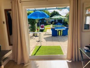 an open door to a patio with an umbrella at Modern bungalow with private swimming pool in Maidenhead