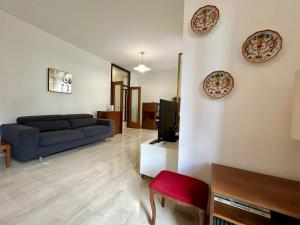 uma sala de estar com um sofá azul e uma TV em Kibilù - Bright Apartment with Large Terrace near Station FN City Centre walking distance em Varese