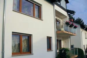 a white building with a balcony with flowers on it at Ferienwohnung Petryk in Weinheim