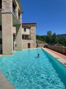 una persona che nuota in una grande piscina blu di House in Tuscany - Casa La Scala a Gaiole in Chianti