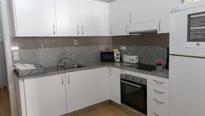 a kitchen with white cabinets and a sink at Sant Jordi Pisos - Consell de Cent in Barcelona