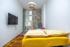 a bedroom with a bed with yellow sheets and a window at Apartmani Leo centar in Crikvenica