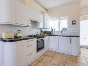 a white kitchen with white cabinets and appliances at Seaspray in St Ives +15 photos