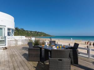 a table and chairs on a deck with the beach at Seaspray in St Ives