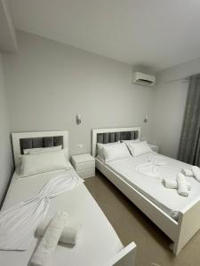 two beds in a room with white walls at Joal Rooms in Sarandë