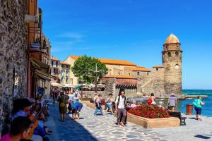a group of people walking down a street with a clock tower at Logement 50 m de la plage Arrivée et Départ Autonome in Collioure