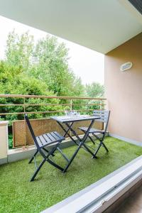 ein Tisch und Stühle auf einem Balkon mit Gras in der Unterkunft Montevrain disney 10mn Parking privé in Montévrain