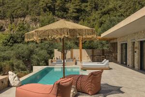 a swimming pool with two chairs and an umbrella at Monalia suites in Parga